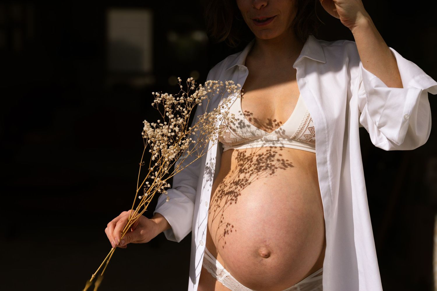 photographe grossesse à domicile avec ombre et lumière et fleurs séchées à Marseille