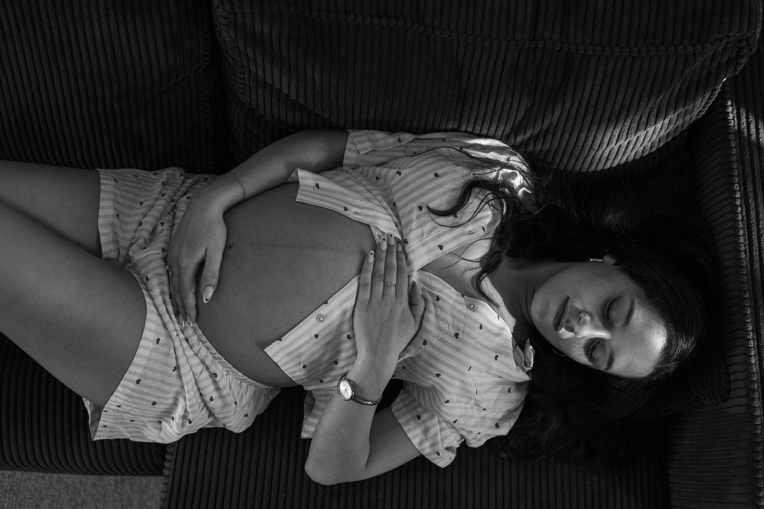 seance photo grossesse à domicile à marseille avec la maman allongée sur son canapé en noir et blanc