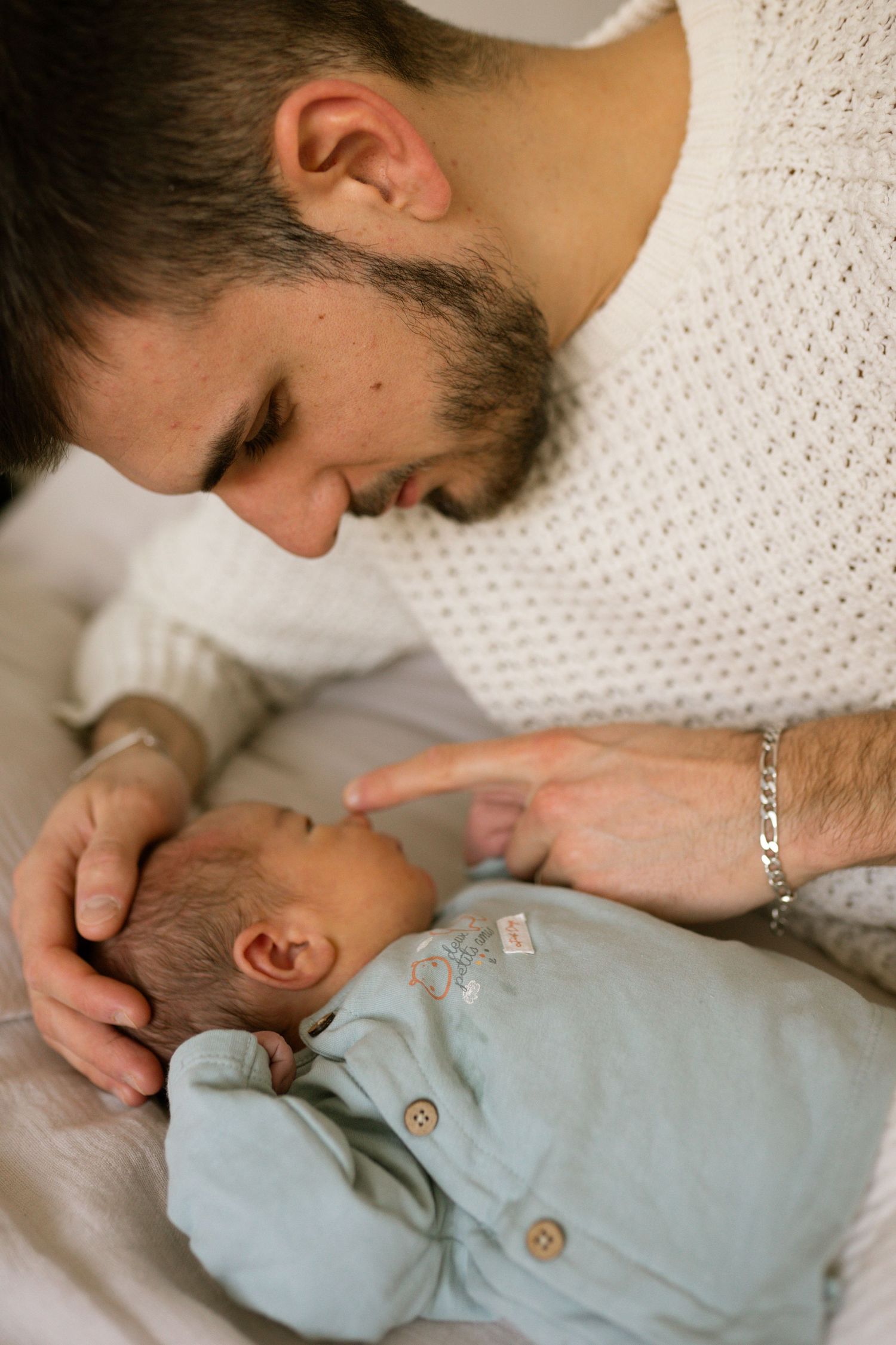 seance photo naissance et famille avec un papa qui câline son bébé dans le lit à Marseille