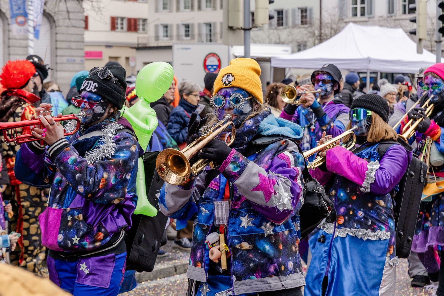 People dressed up in costumes walk in a parade and play trumpets.