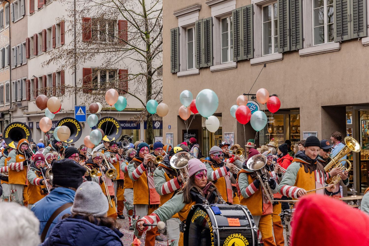 Balloons and people in costumes during a parade making loud music