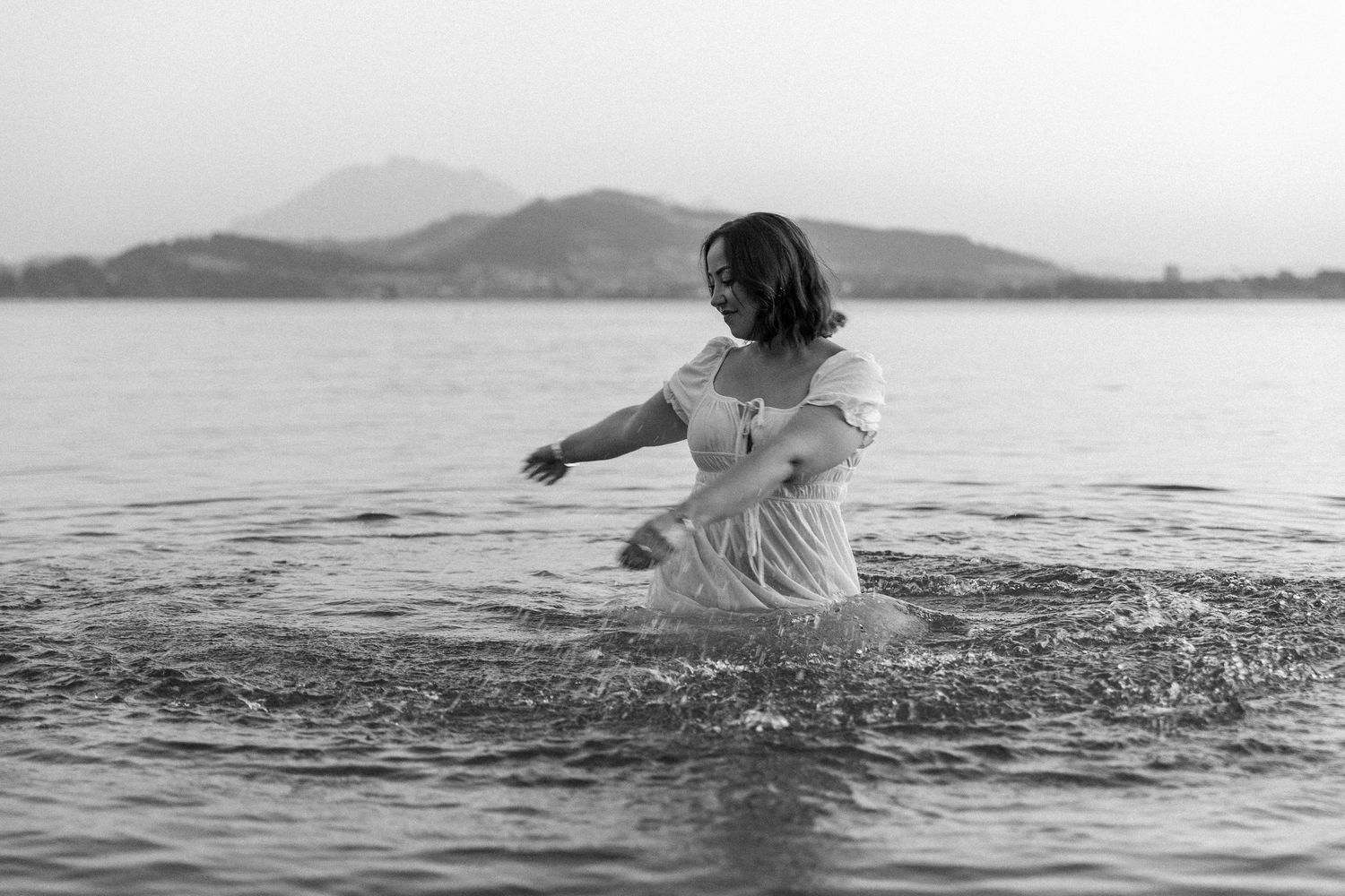 A lifestyle shoot in the lake during golden hour where the model is playing in the water in a white dress