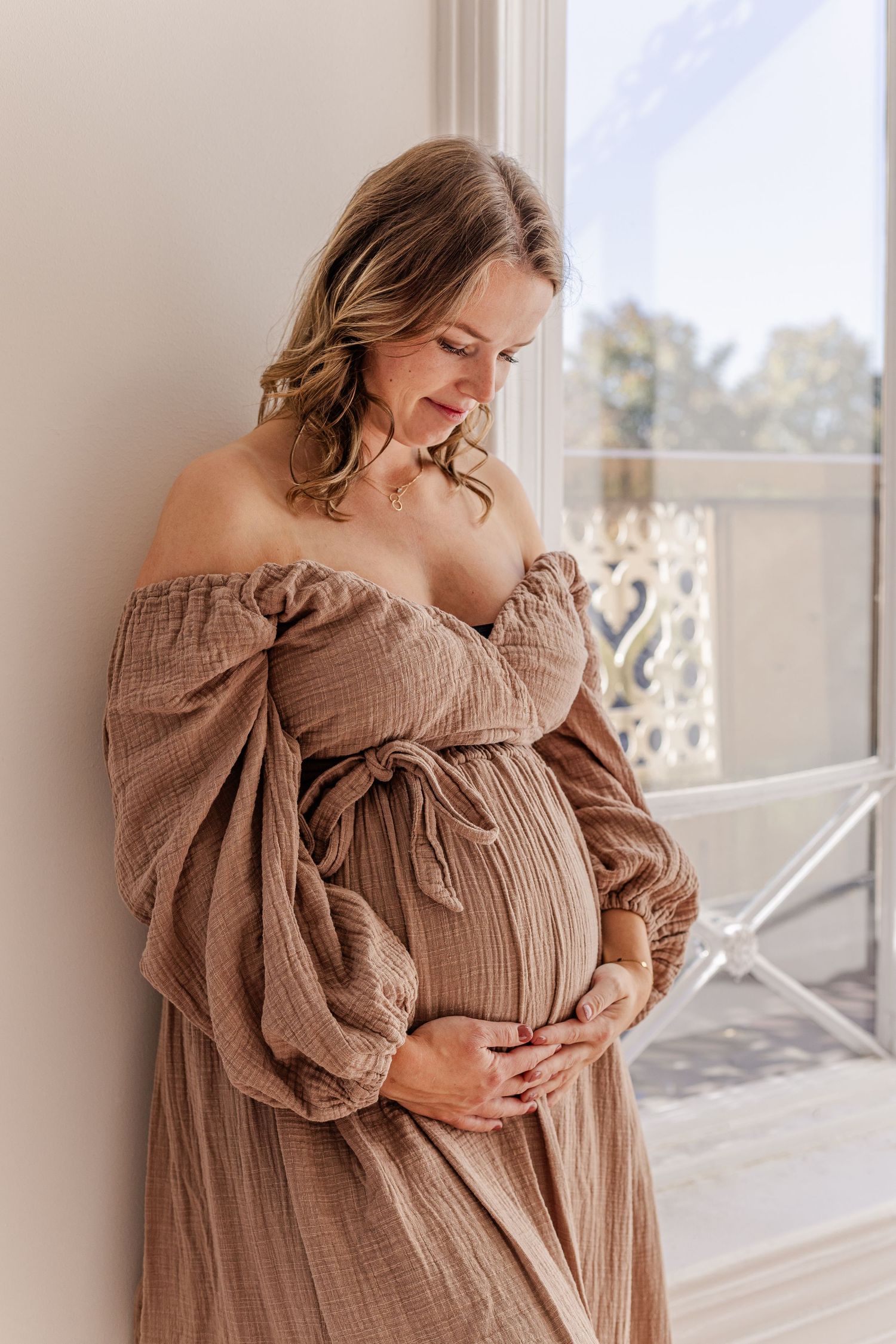 A pregnant woman looking happy to her belly during an indoor shoot with natural light