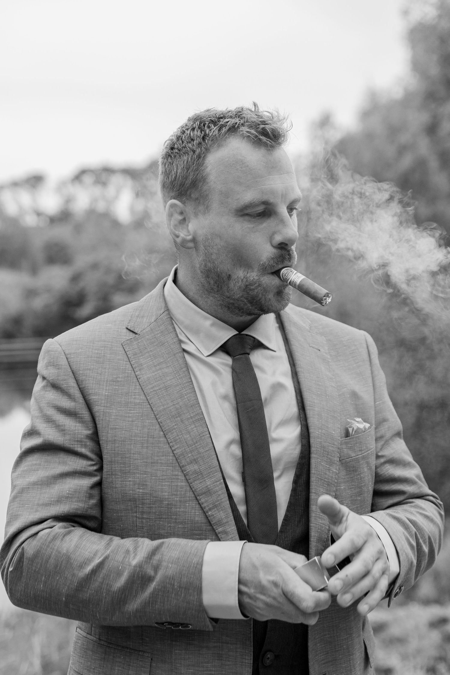 Man in a suit smoking a cigar with smoke around him