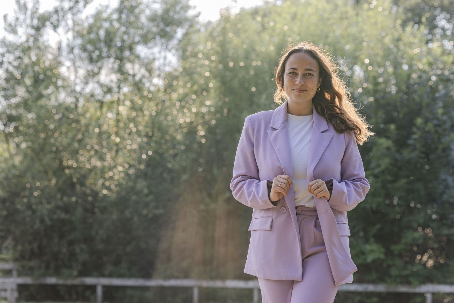 Young entrepreneur in a purple suit smiling into the camera with a beautiful light in the background during a lifestyle branding session