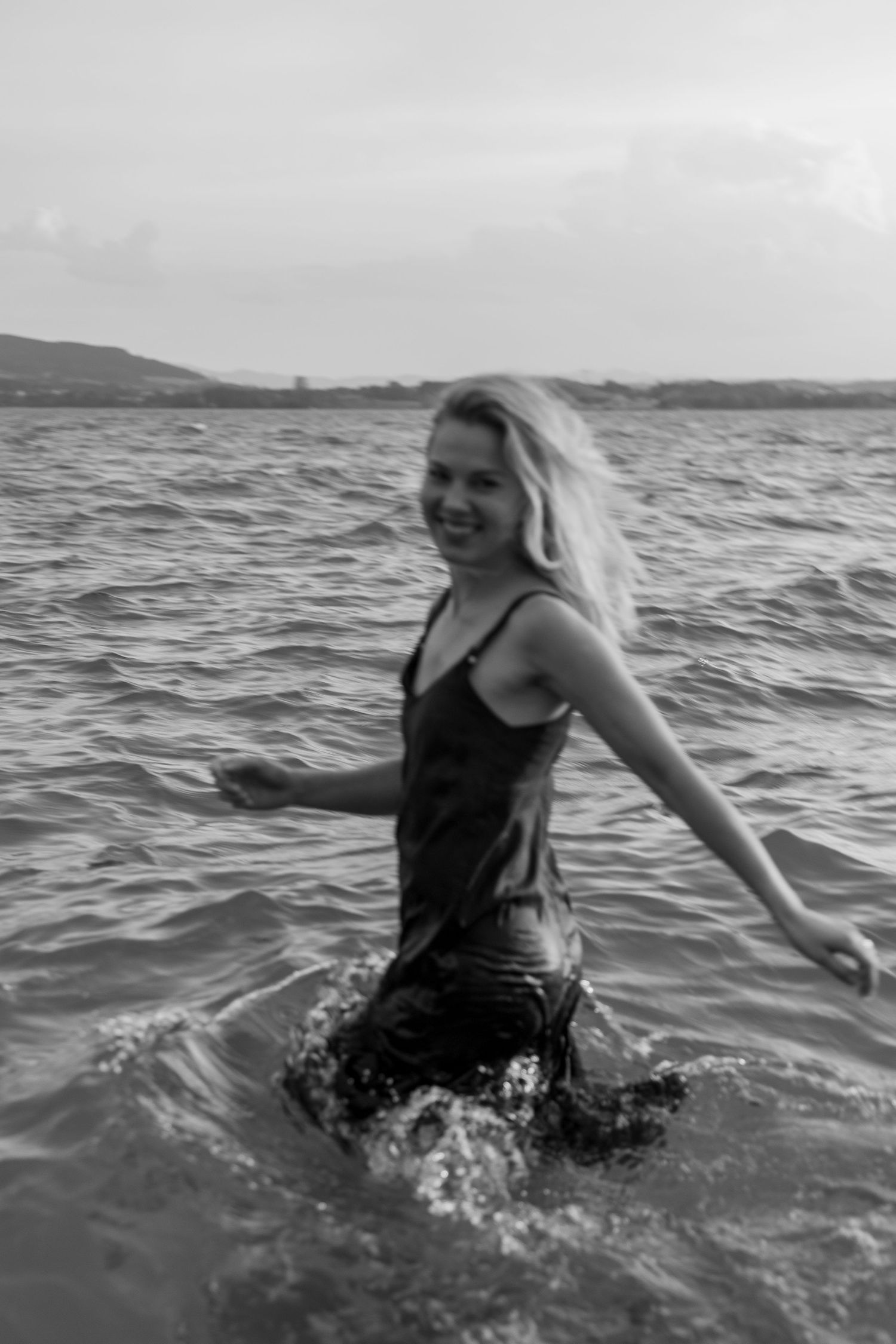 A black and white photo of a woman in black dress having fun during the photoshoot
