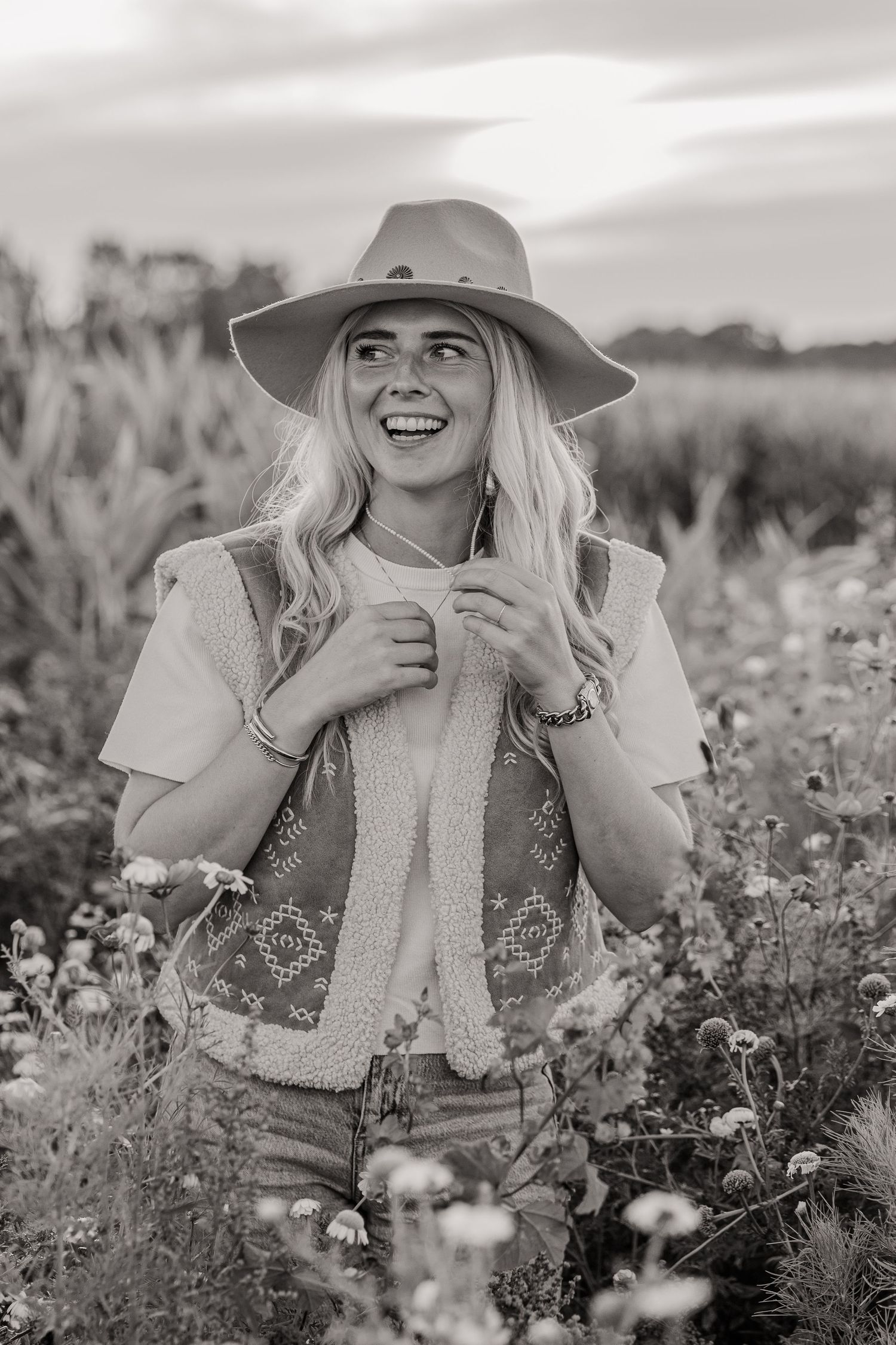 Cowboy girl in a flower field during golden hour