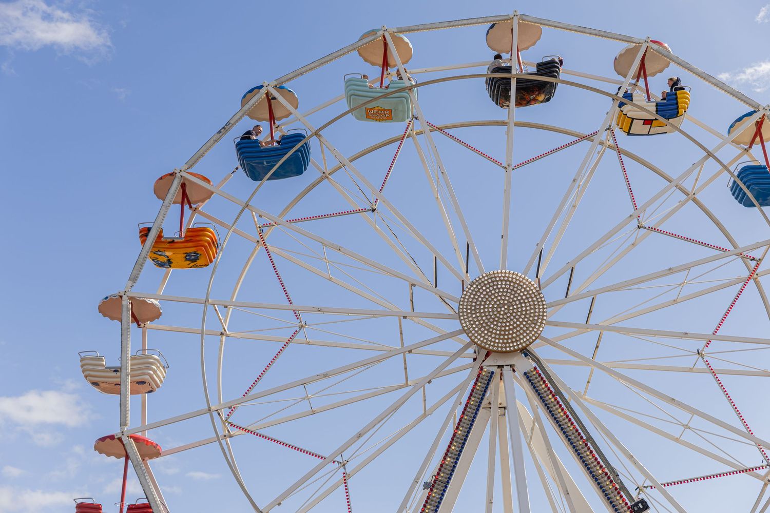 Ferris wheel with colorful seats photographed against a blue sky