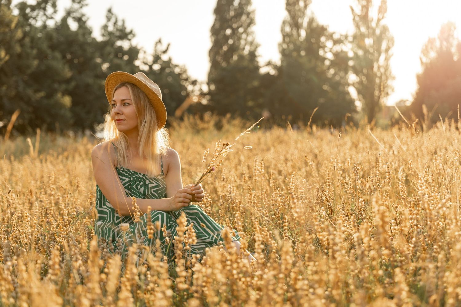 Woman sitting in the grass with a head during a golden hour lifestyle photoshoot