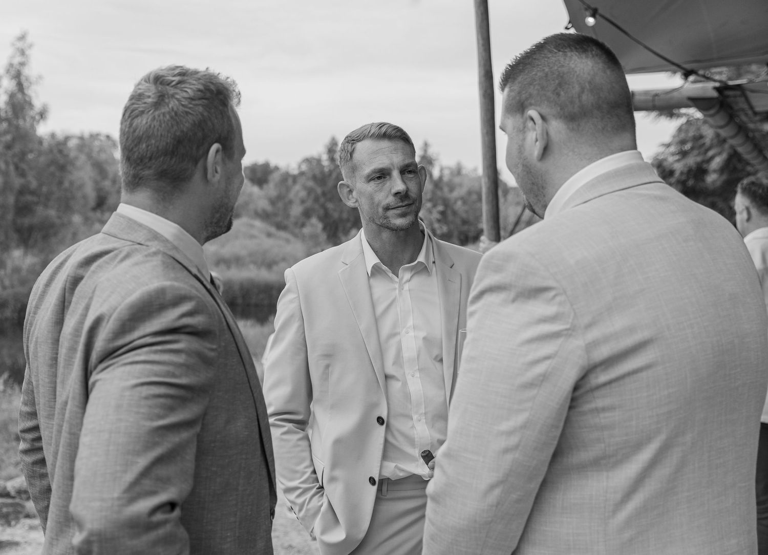 The groom and two friends having a conversation during a wedding ceremony