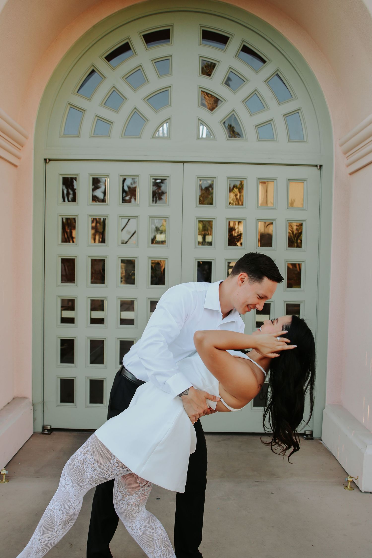 Romantic couple performs a dance dip pose against a beautiful arched doorway background.