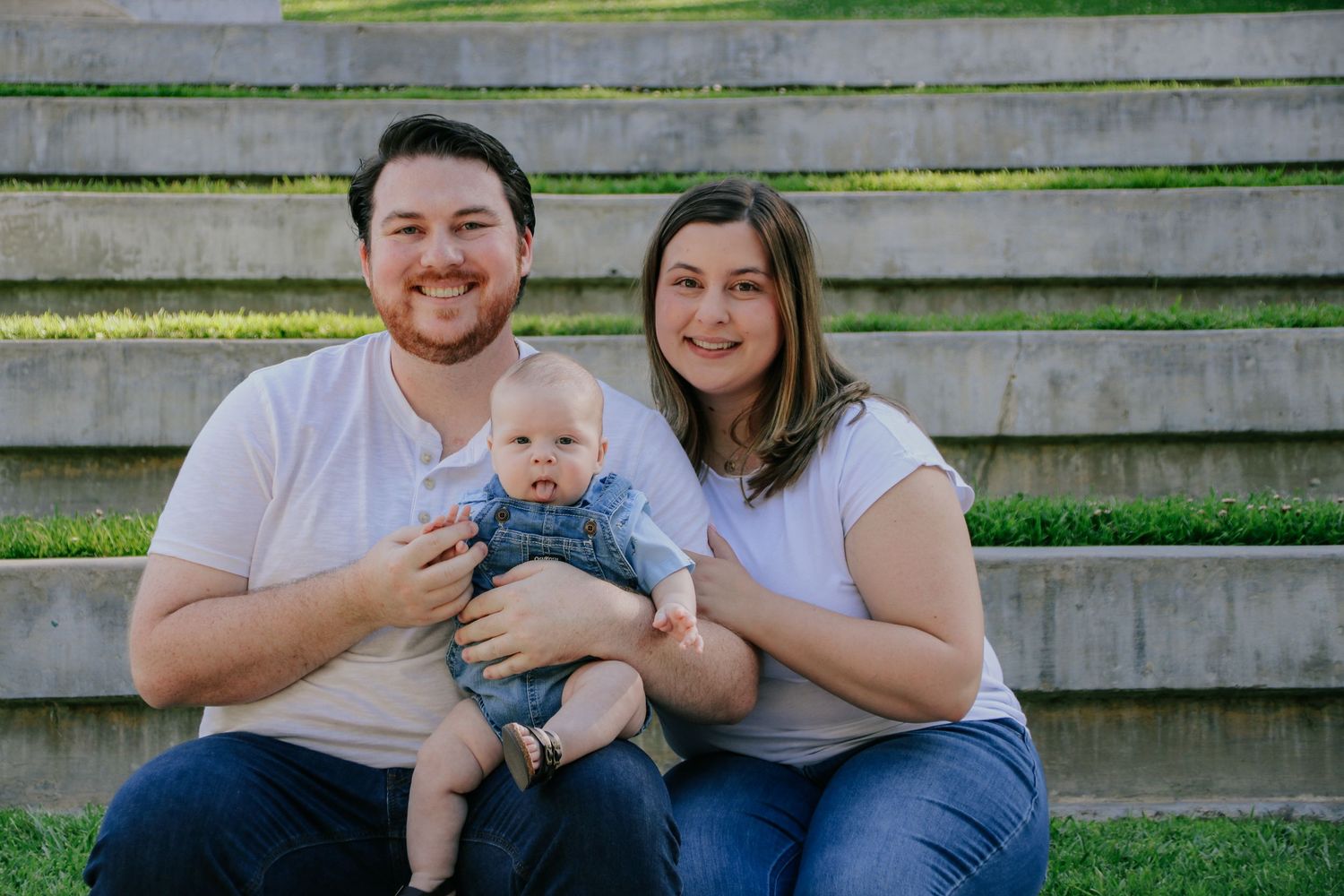 Casual family portraits taken on wooden bleachers showing parents with their infant.
