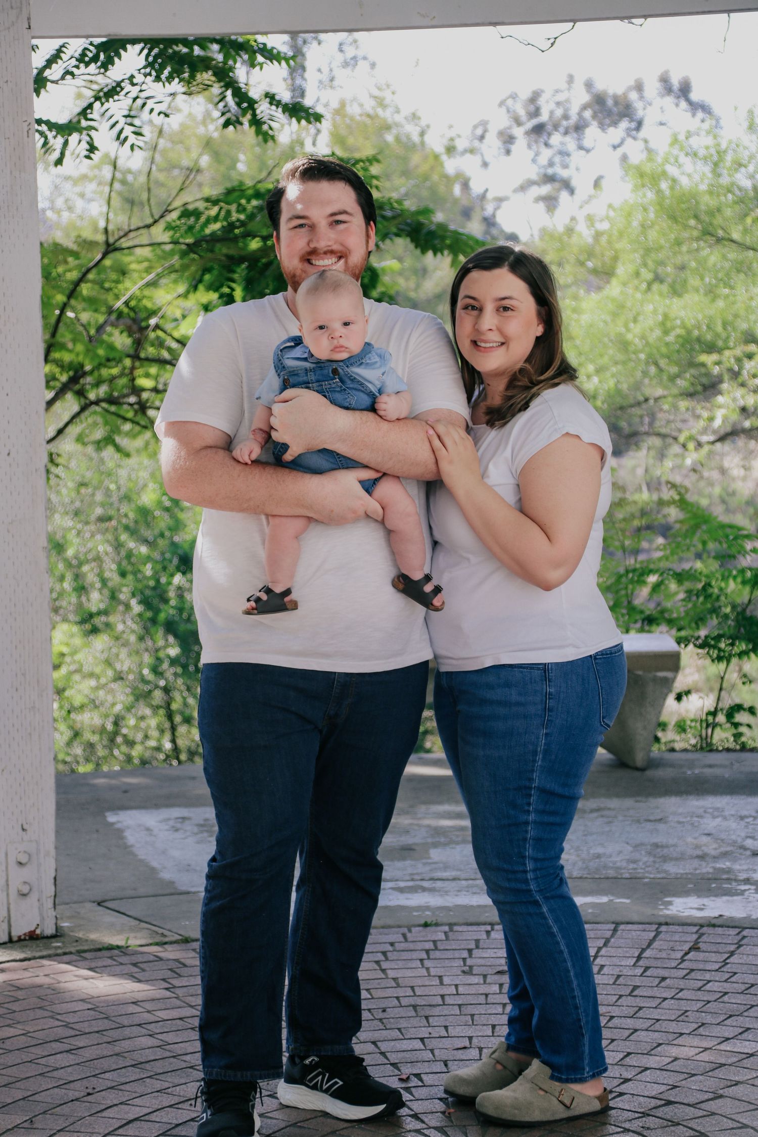 A family portrait taken on a brick patio with trees and mountains visible in the background.