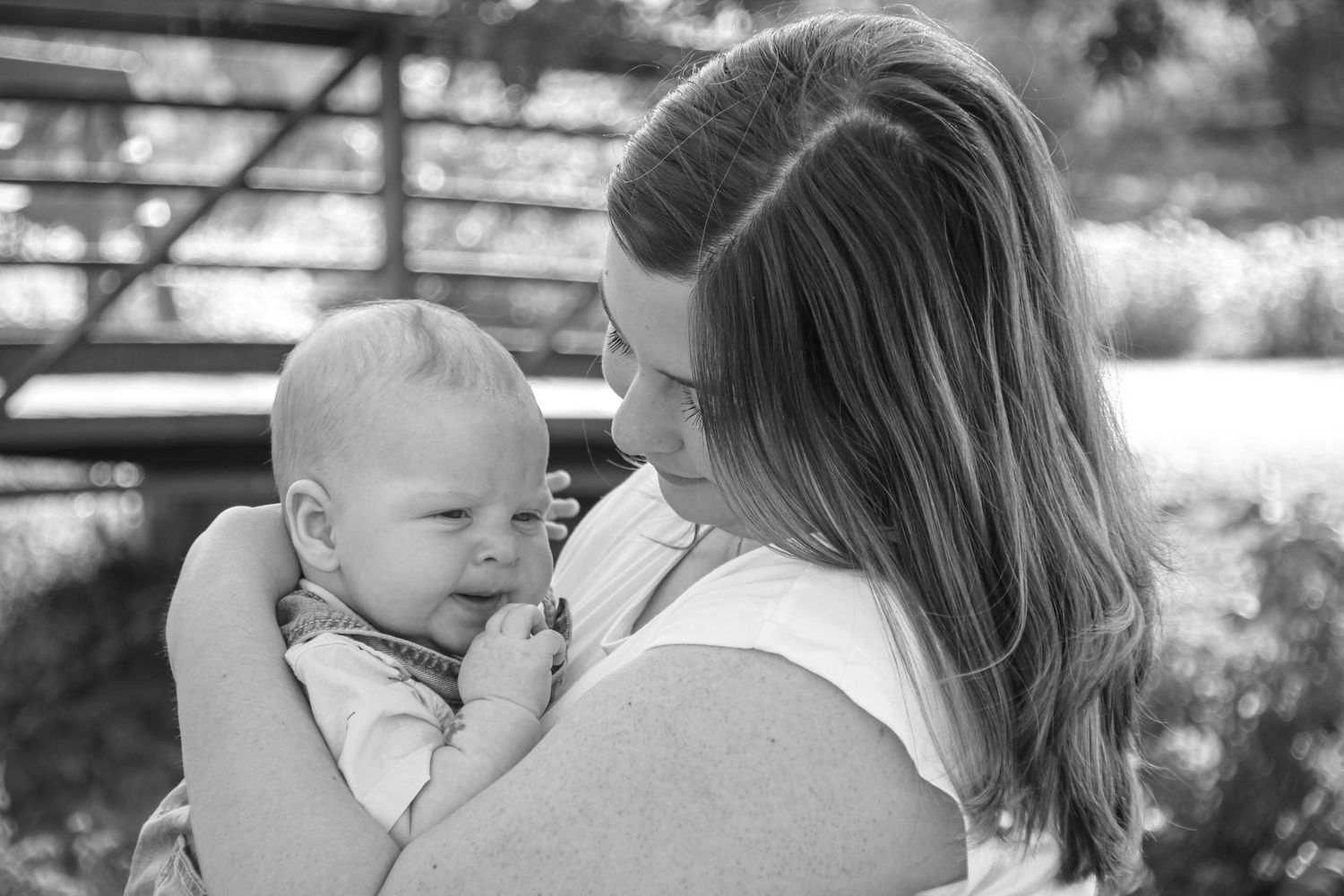 Intimate black and white series of mother holding baby against rustic backdrop.