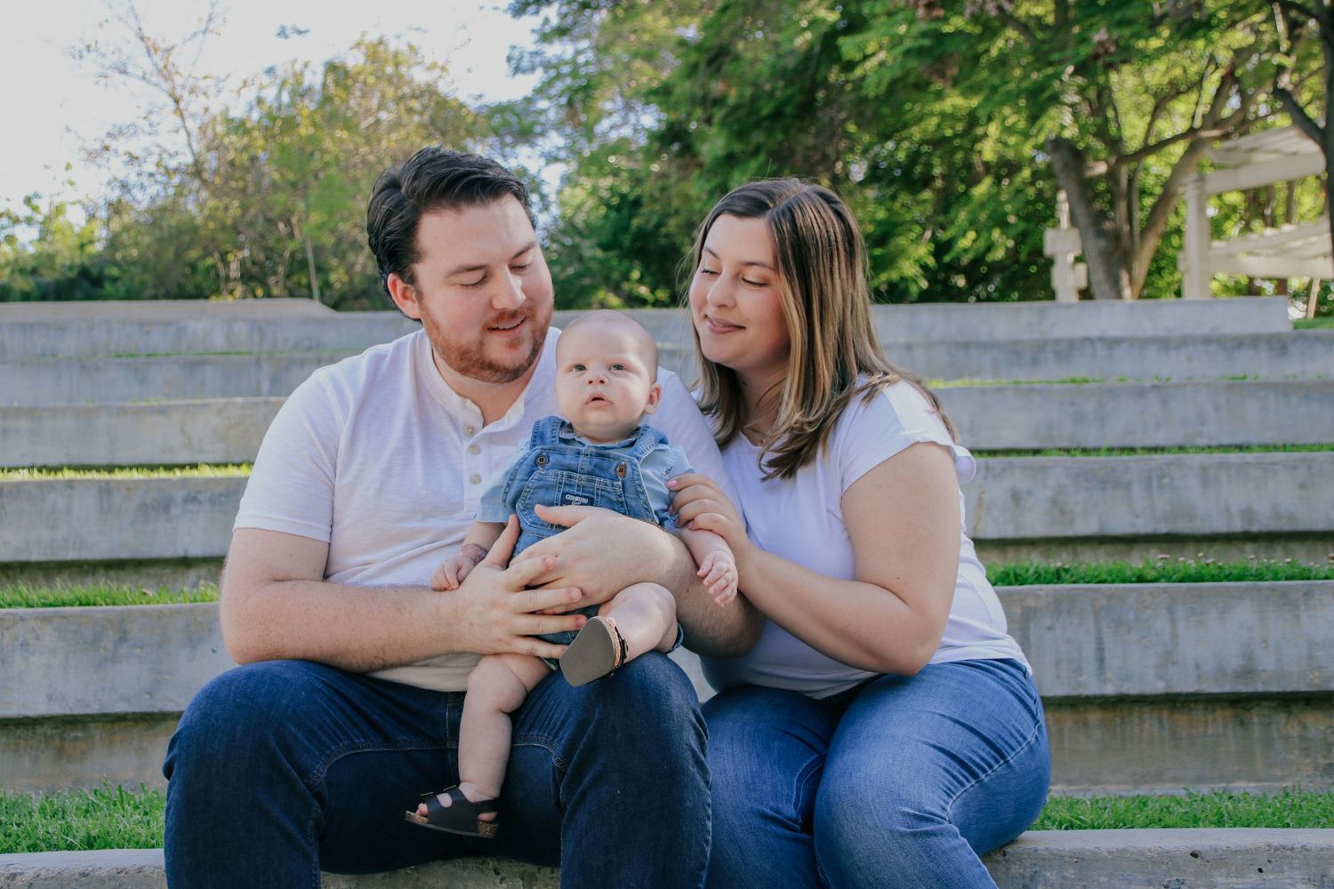 Natural light family portraits showing loving moments between parents and baby outdoors.