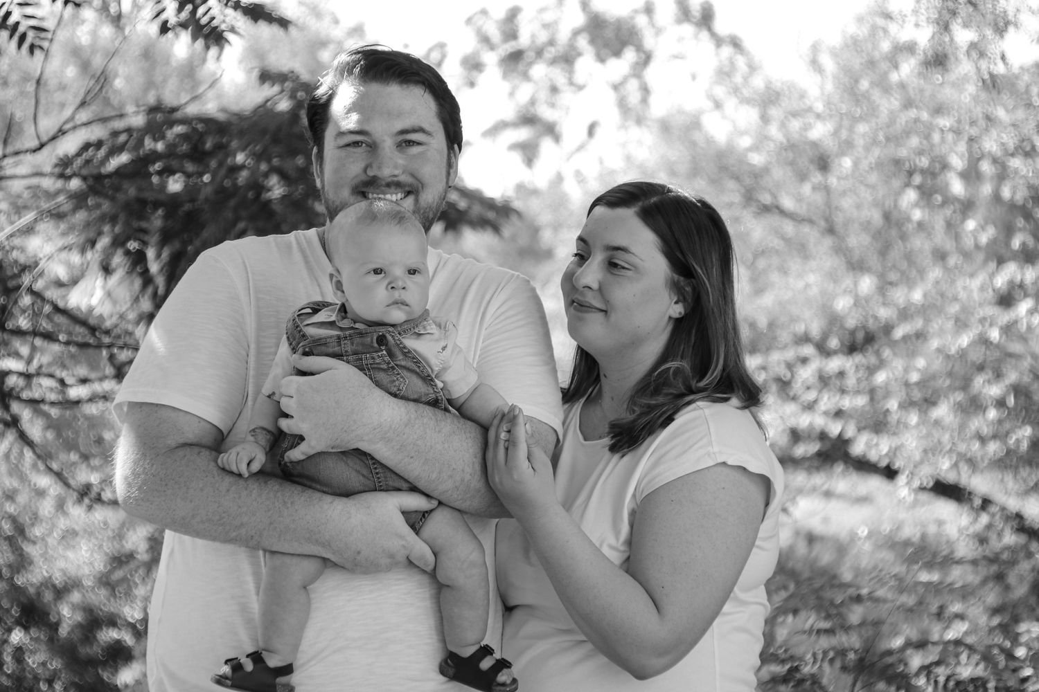 A black and white outdoor family portrait capturing natural expressions and genuine emotions.