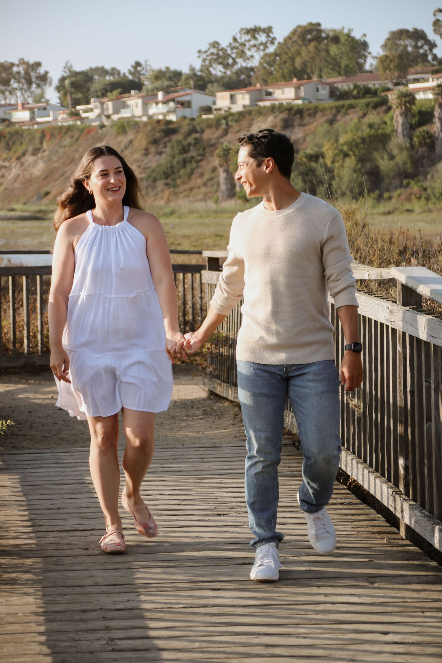 Happy couple enjoying a casual walk together on a seaside boardwalk during golden hour.