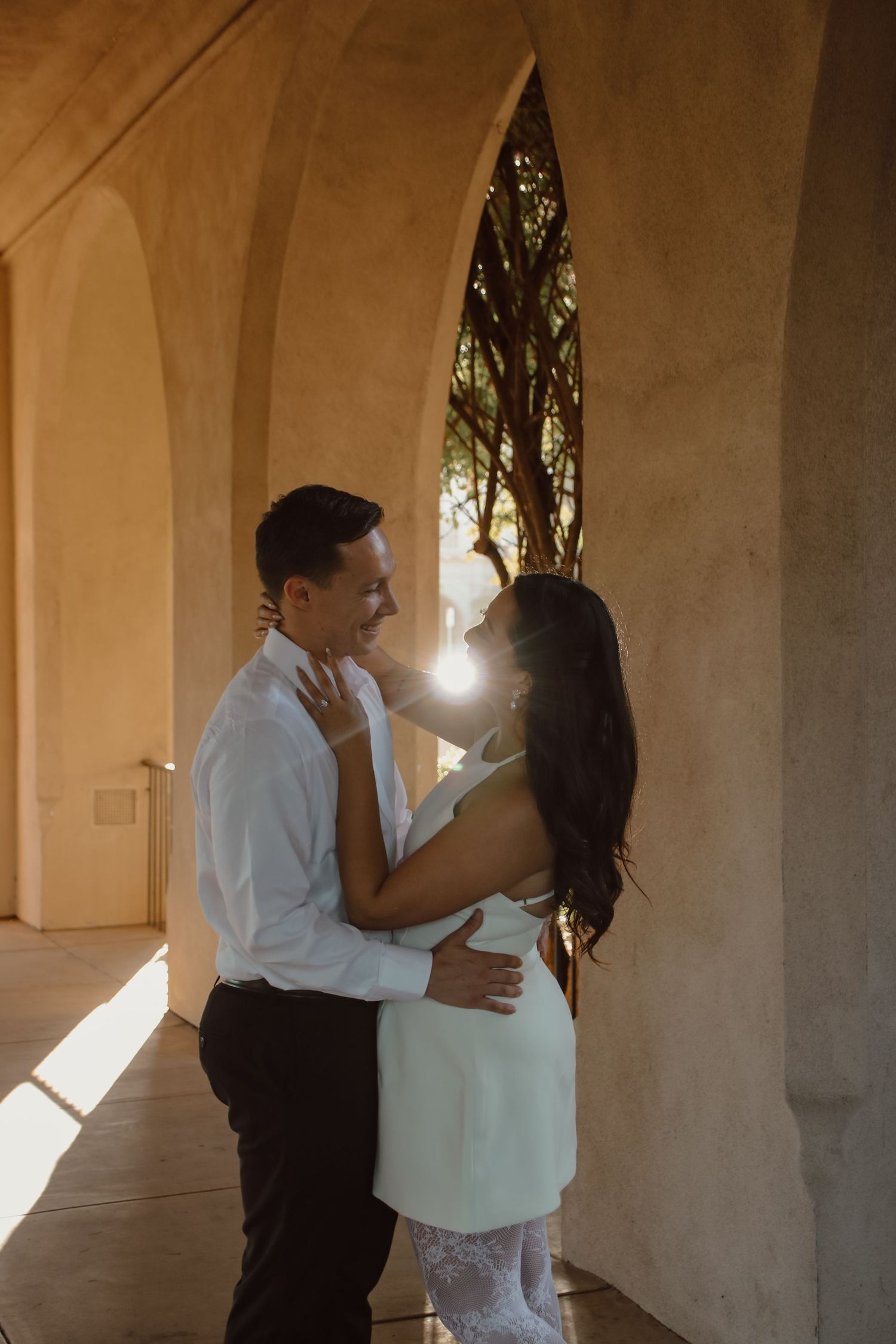 Two people sharing intimate dance moves in a covered outdoor walkway with natural light.