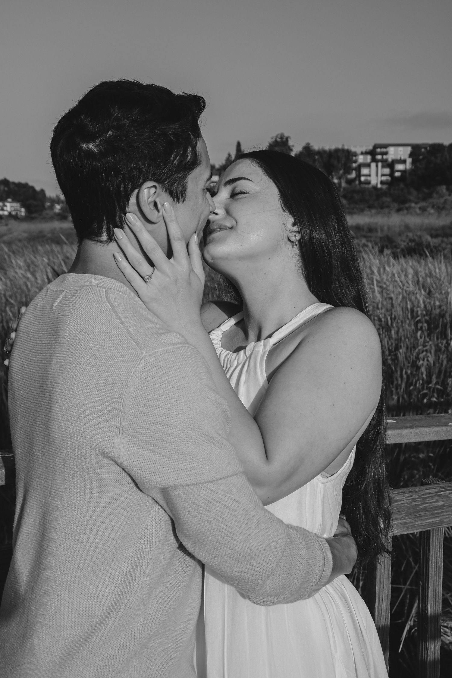 Black and white photo of romantic couple kissing outdoors.