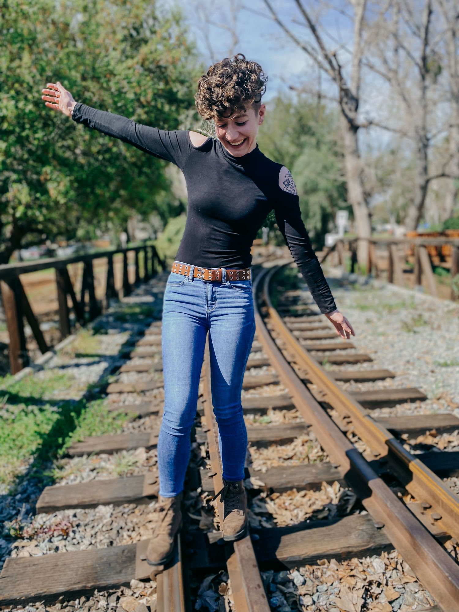 Someone performing balancing poses while walking along old train tracks through wooded area.