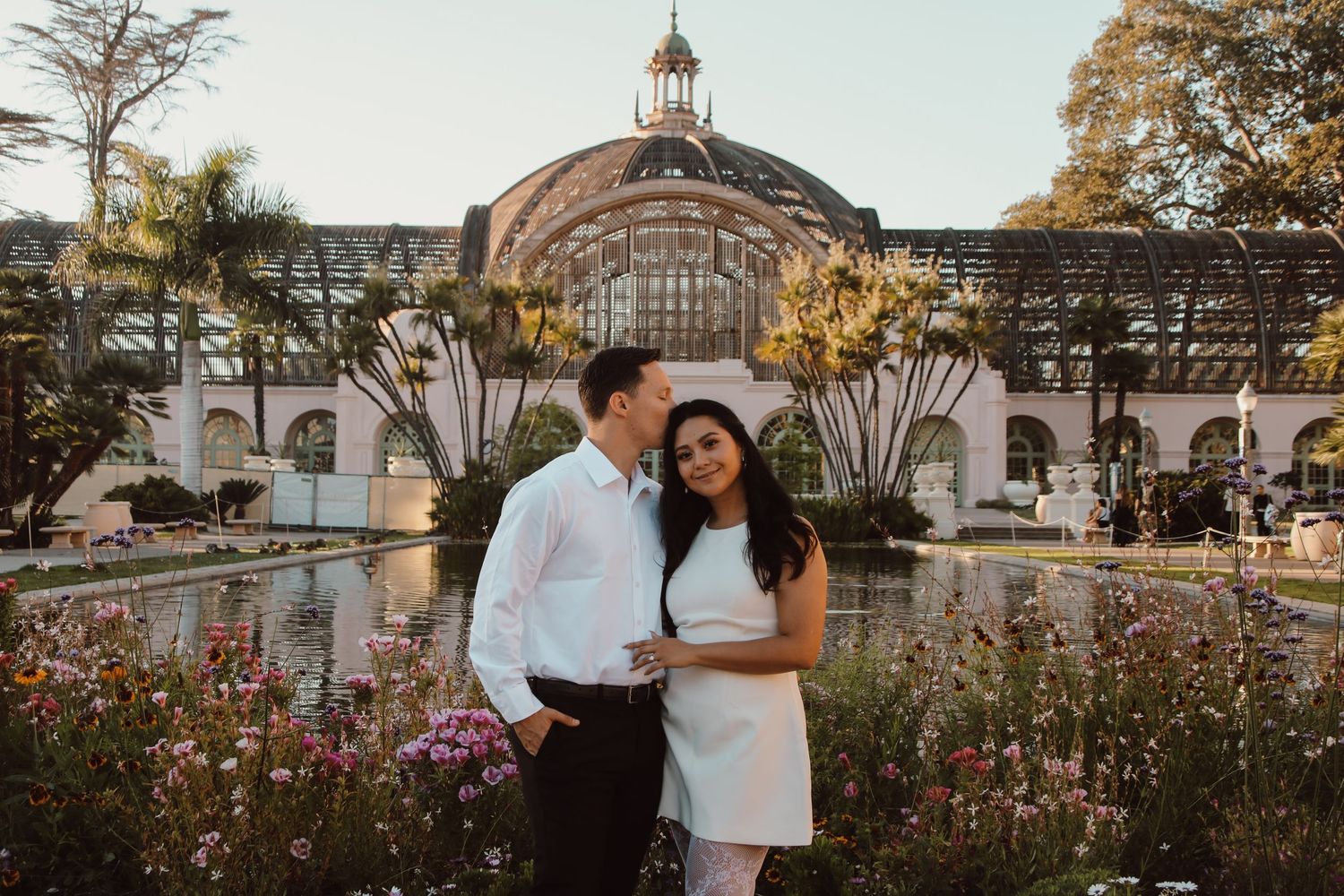 Engagement photos captured in a garden setting with classical architecture and flowering plants.