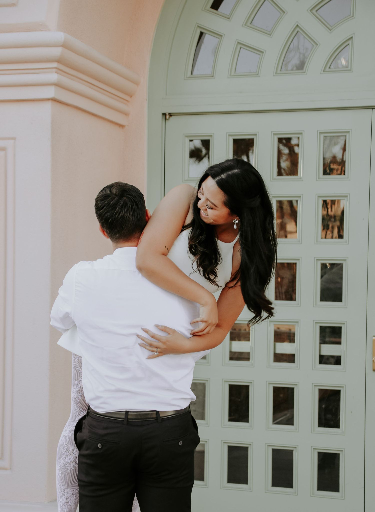 Romantic couple sharing an intimate moment against a white arched doorway background.