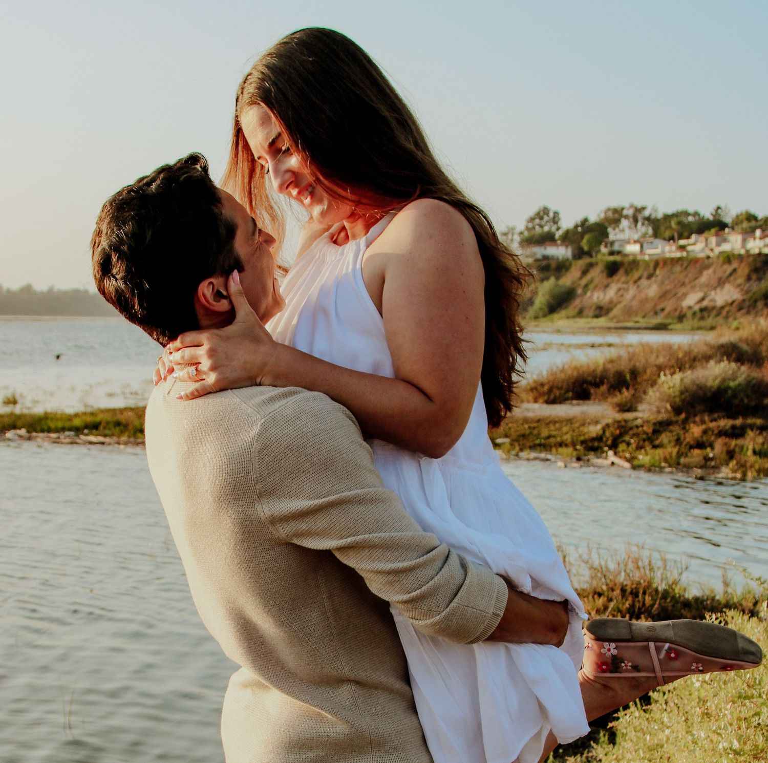 Romantic couple embraces during sunset at a coastal overlook.