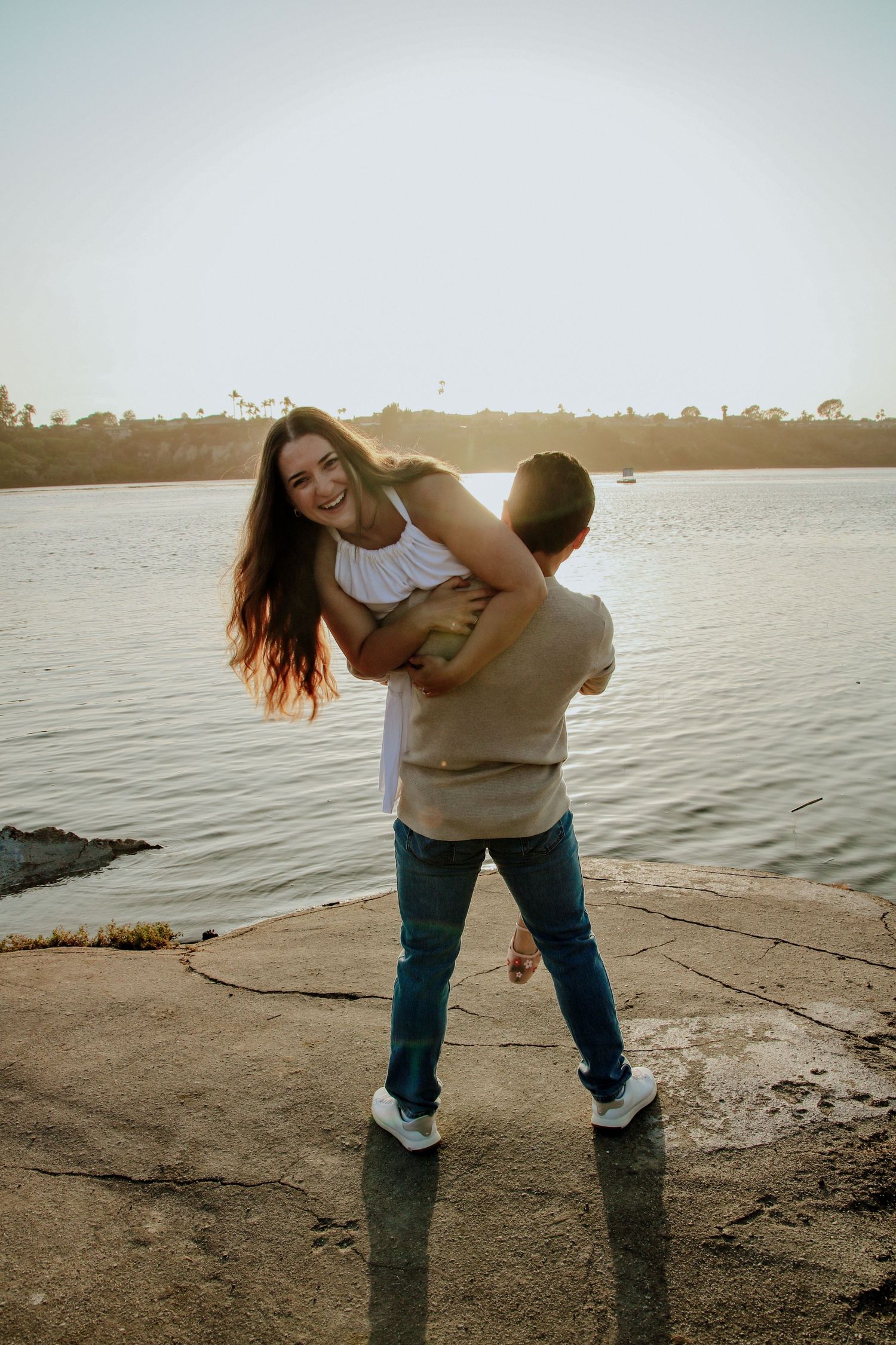 A playful sunset moment captured between a couple at the waterfront.