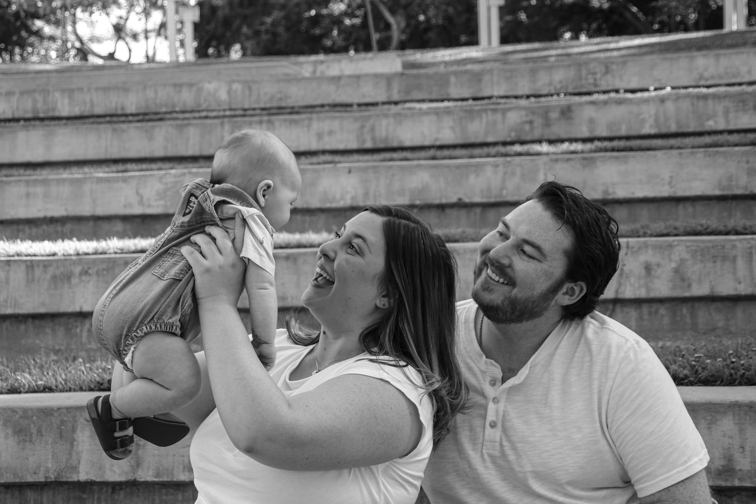 Family shares candid outdoor moments together sitting on concrete steps in matching white outfits.