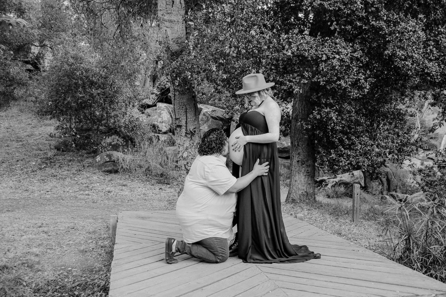 A heartfelt black and white moment captured between two people on a wooden platform outdoors.