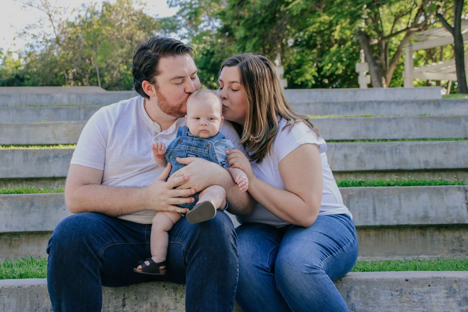 Candid family photography session capturing sweet moments between parents and baby on wooden steps.