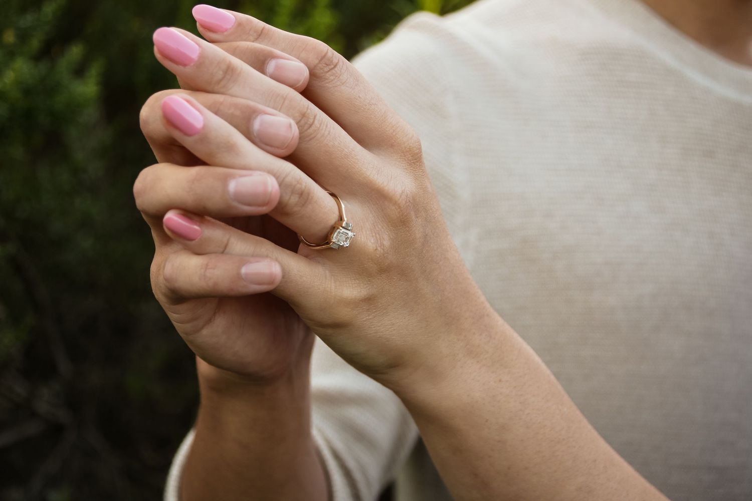 Close-up of hands wearing engagement ring shot in nature.