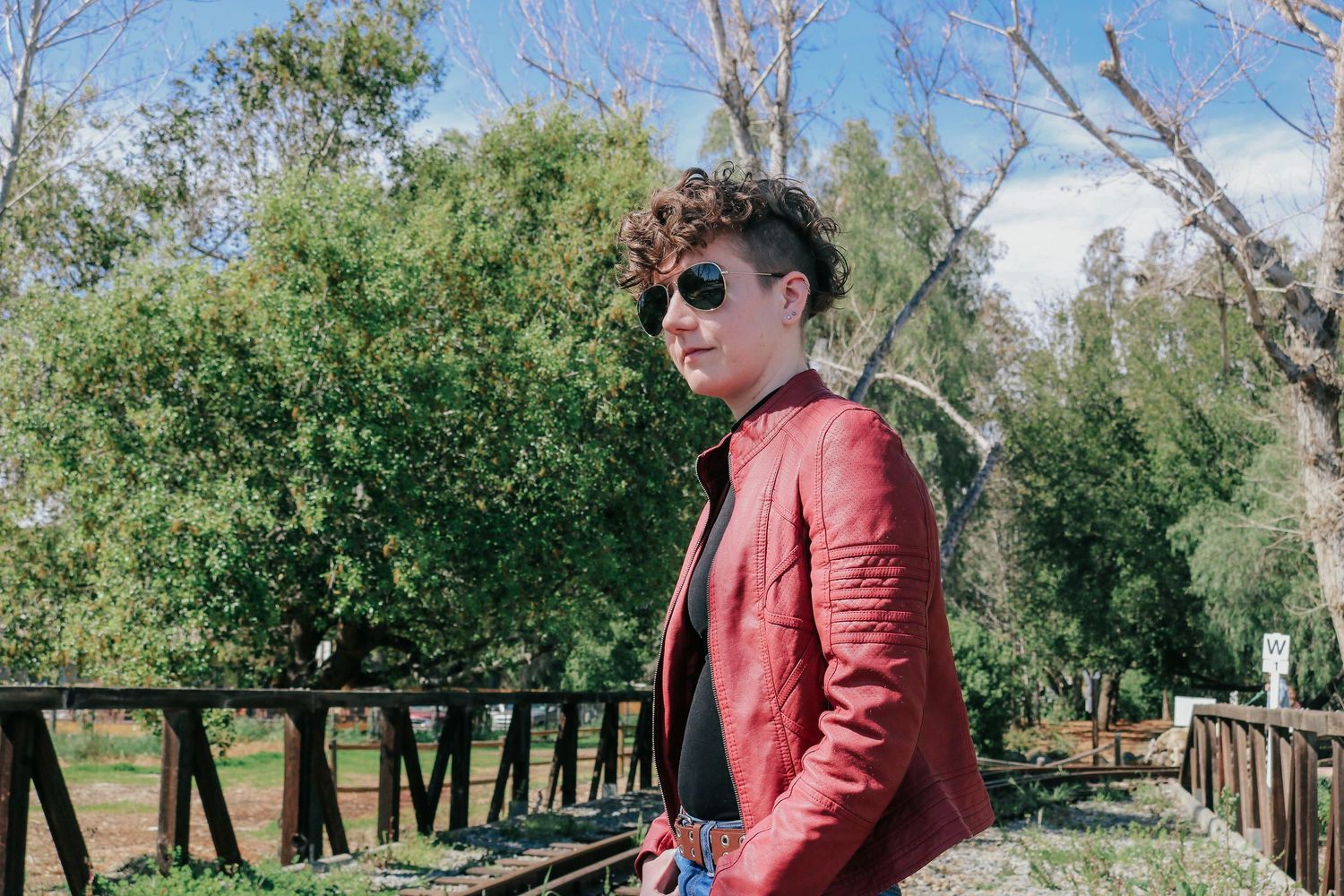 Scenic outdoor fashion photo series along rustic train tracks surrounded by trees.