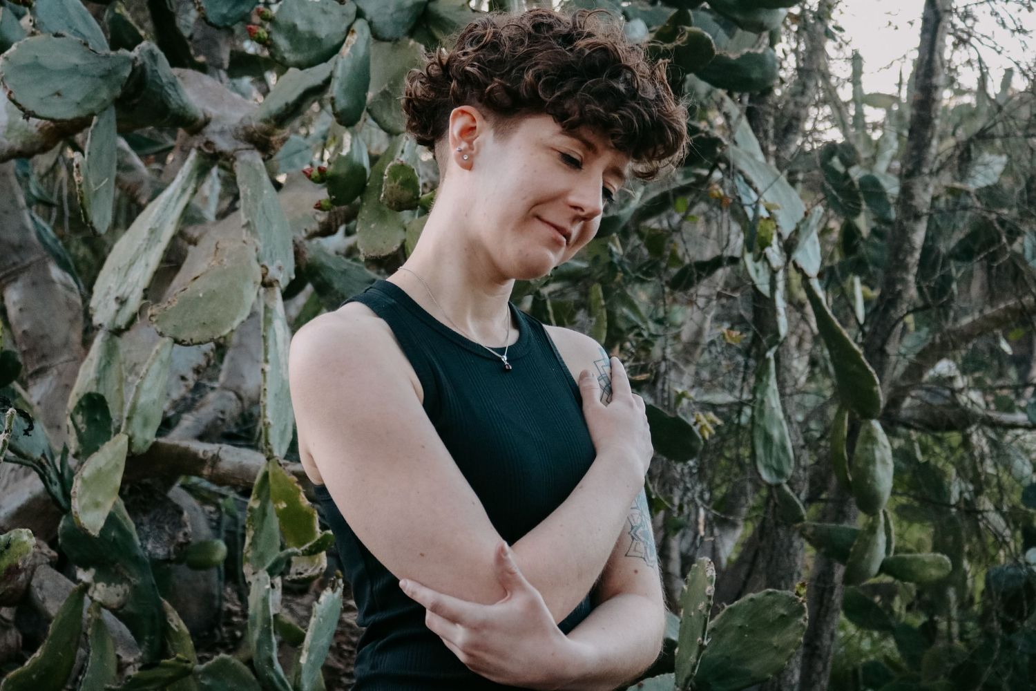 Candid moment captured against cactus background in sleeveless black top.