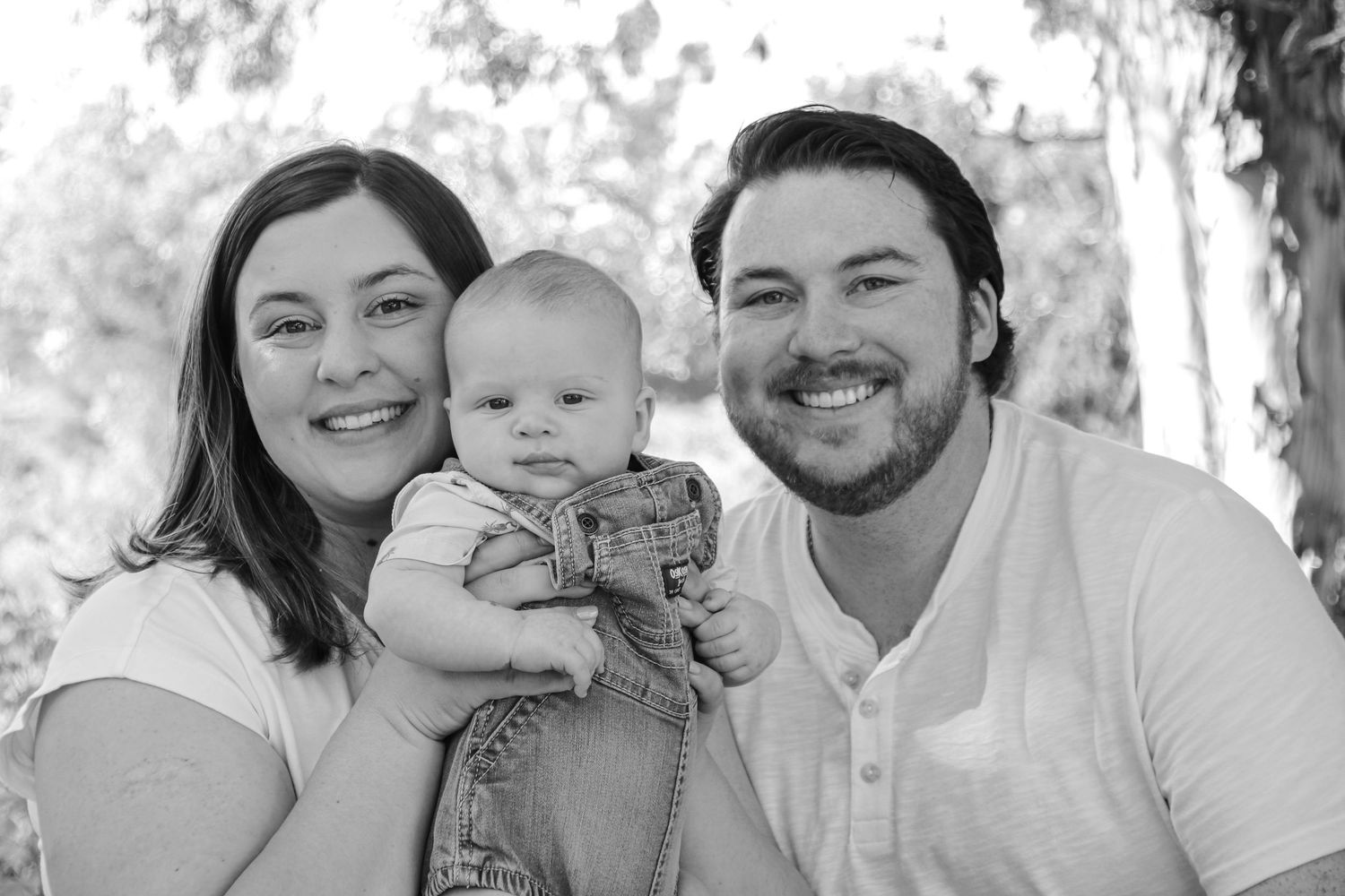 A cheerful black and white family portrait taken outdoors with everyone smiling at the camera.