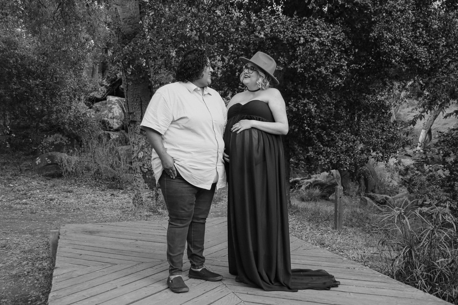 Intimate black and white portrait of couple on wooden platform in natural setting.