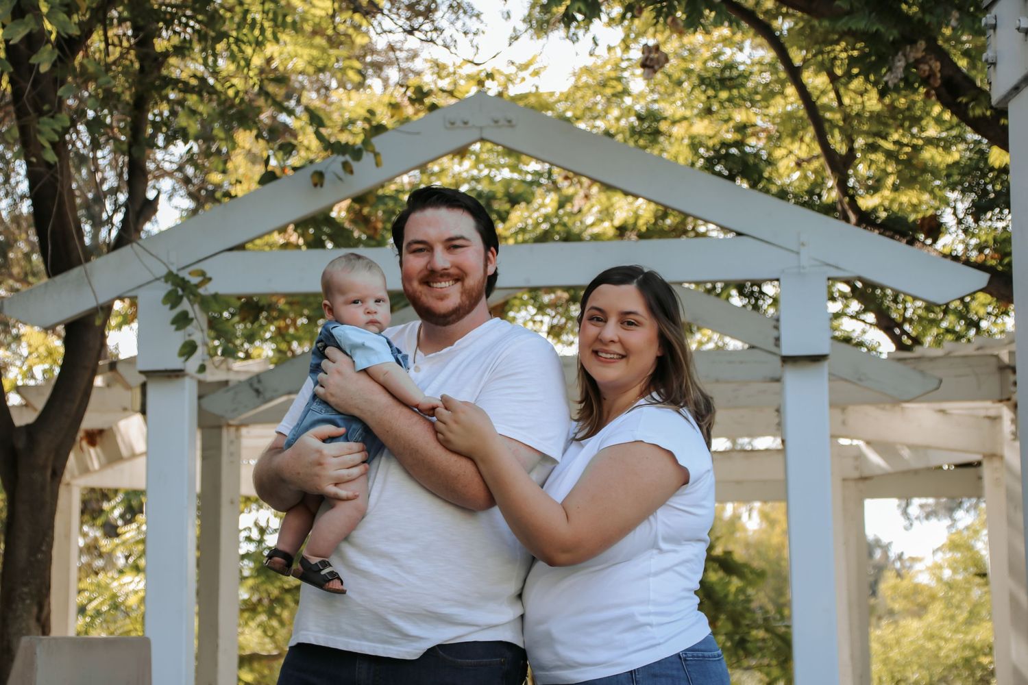 Family portrait session under white gazebo with natural lighting and greenery.