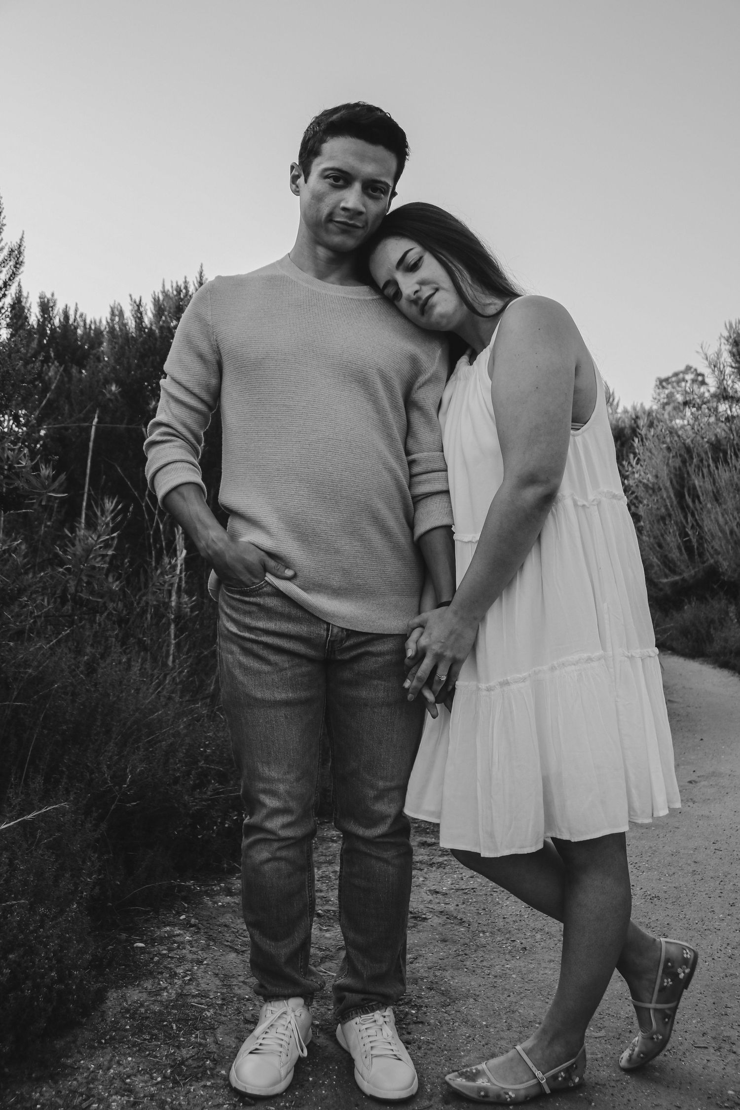 Artistic black and white shot of couple embracing on outdoor trail.