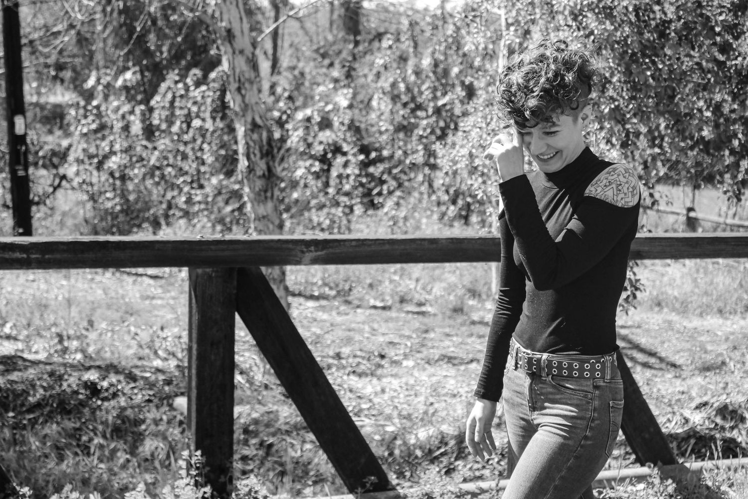Black and white photo of someone walking carefully on old railroad tracks in an outdoor setting.