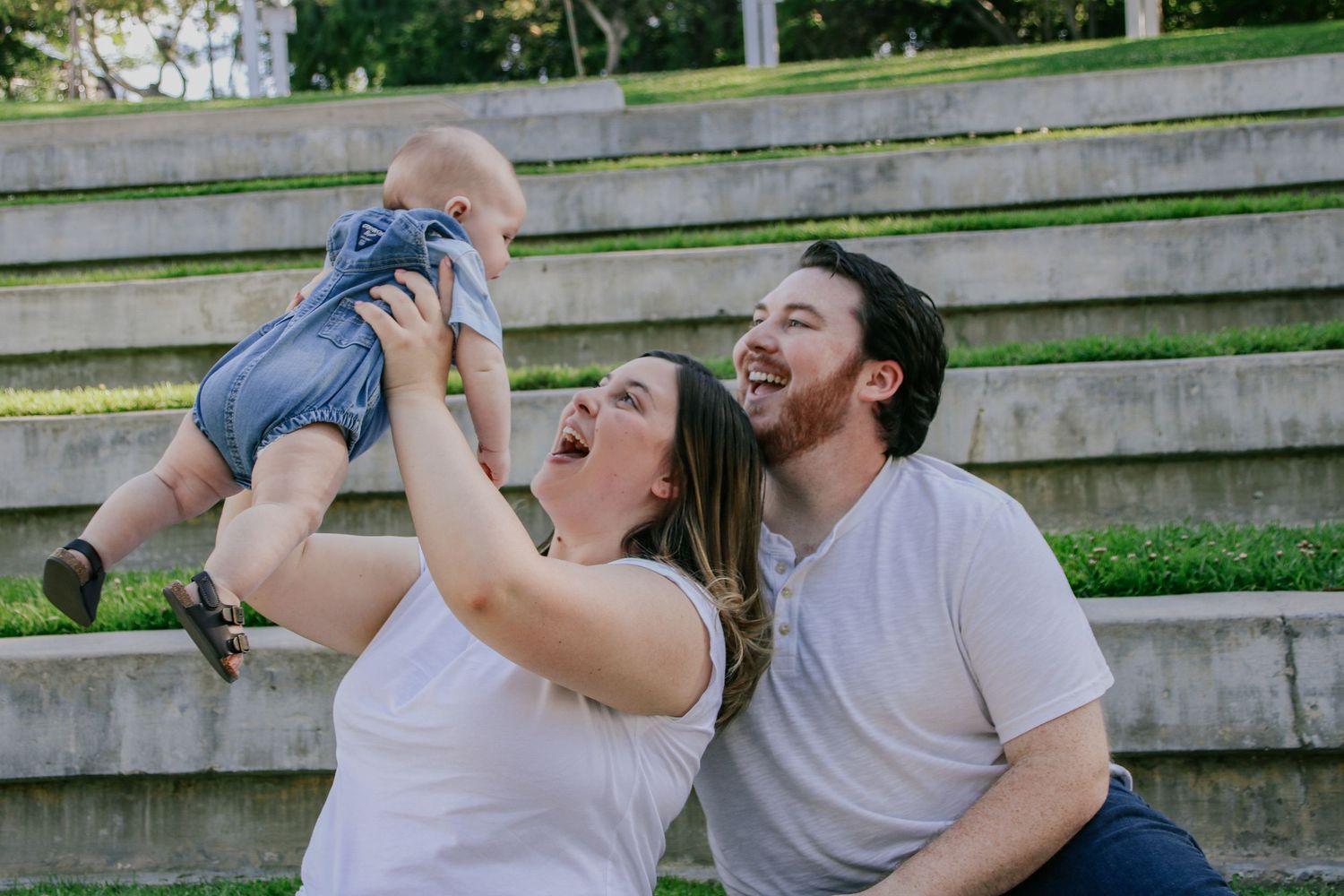 A joyful family moment captured on concrete steps in a park setting.