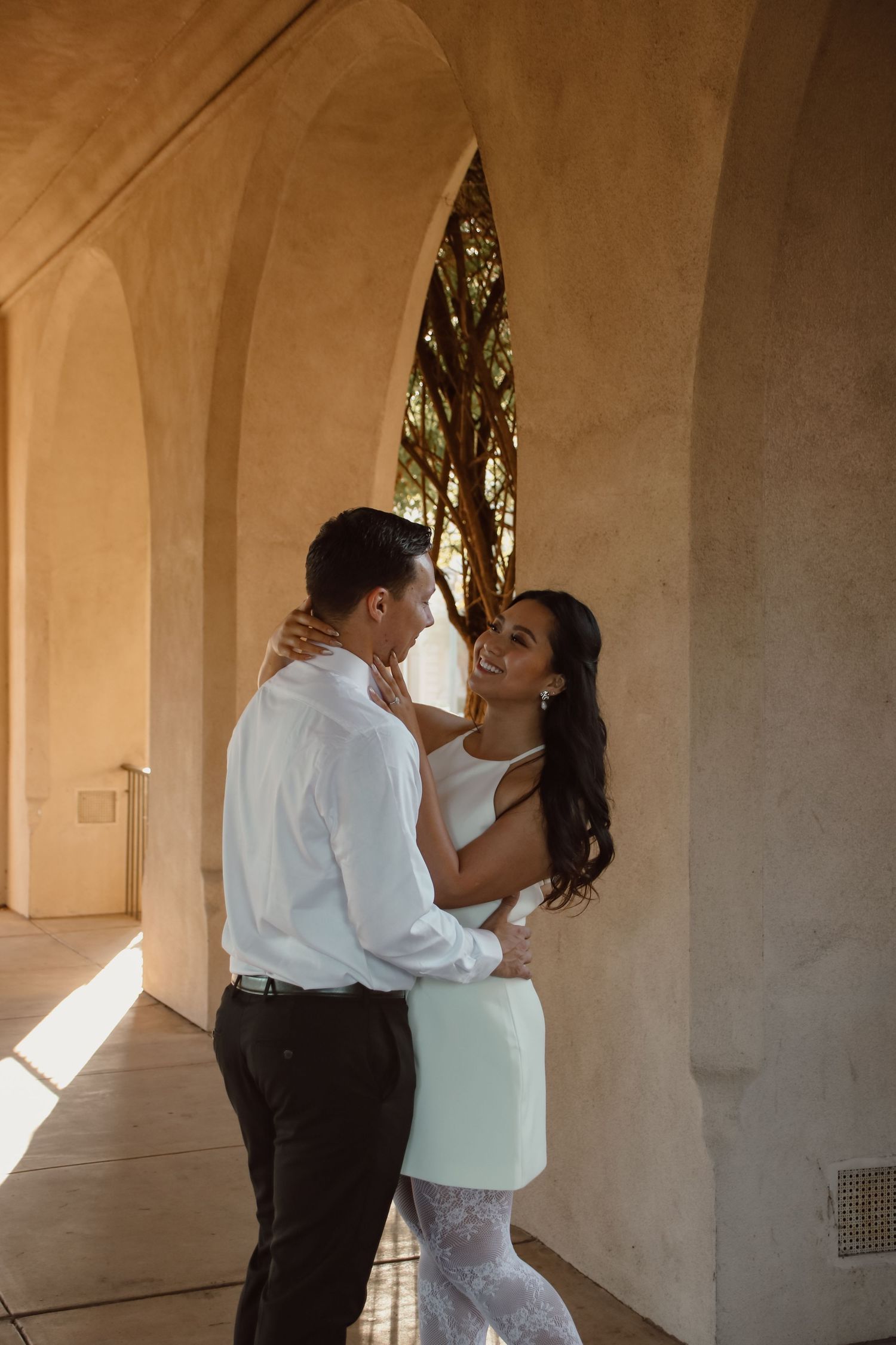 Intimate moments between a couple shared in a sunlit colonnade.