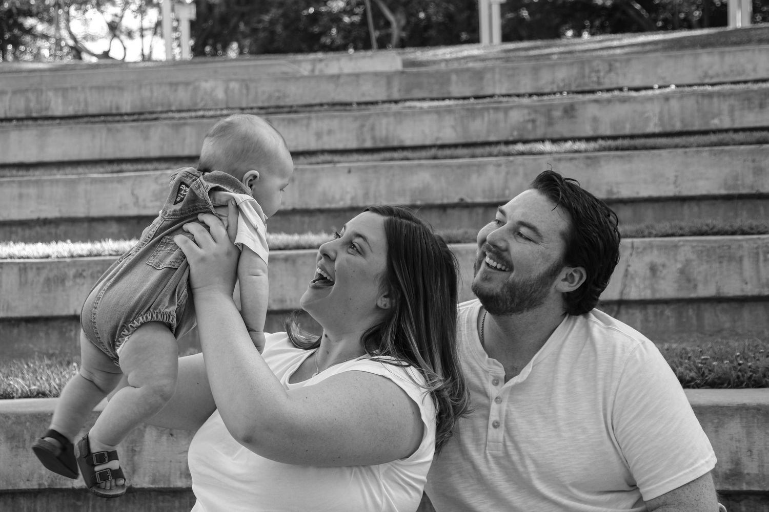 Family shares candid outdoor moments together sitting on concrete steps in matching white outfits.