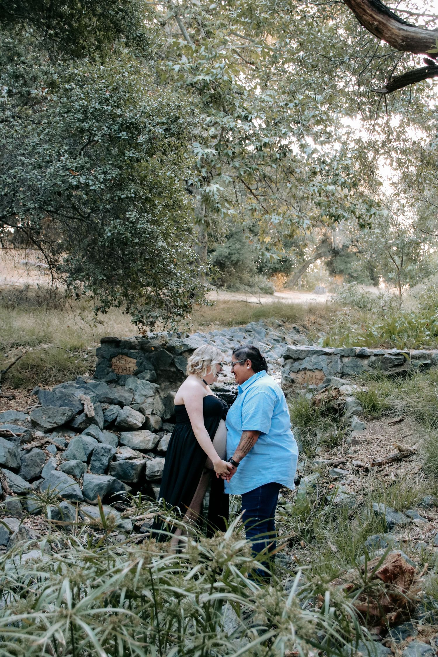 People resting on rocky terrain surrounded by trees and vegetation in a serene outdoor environment.