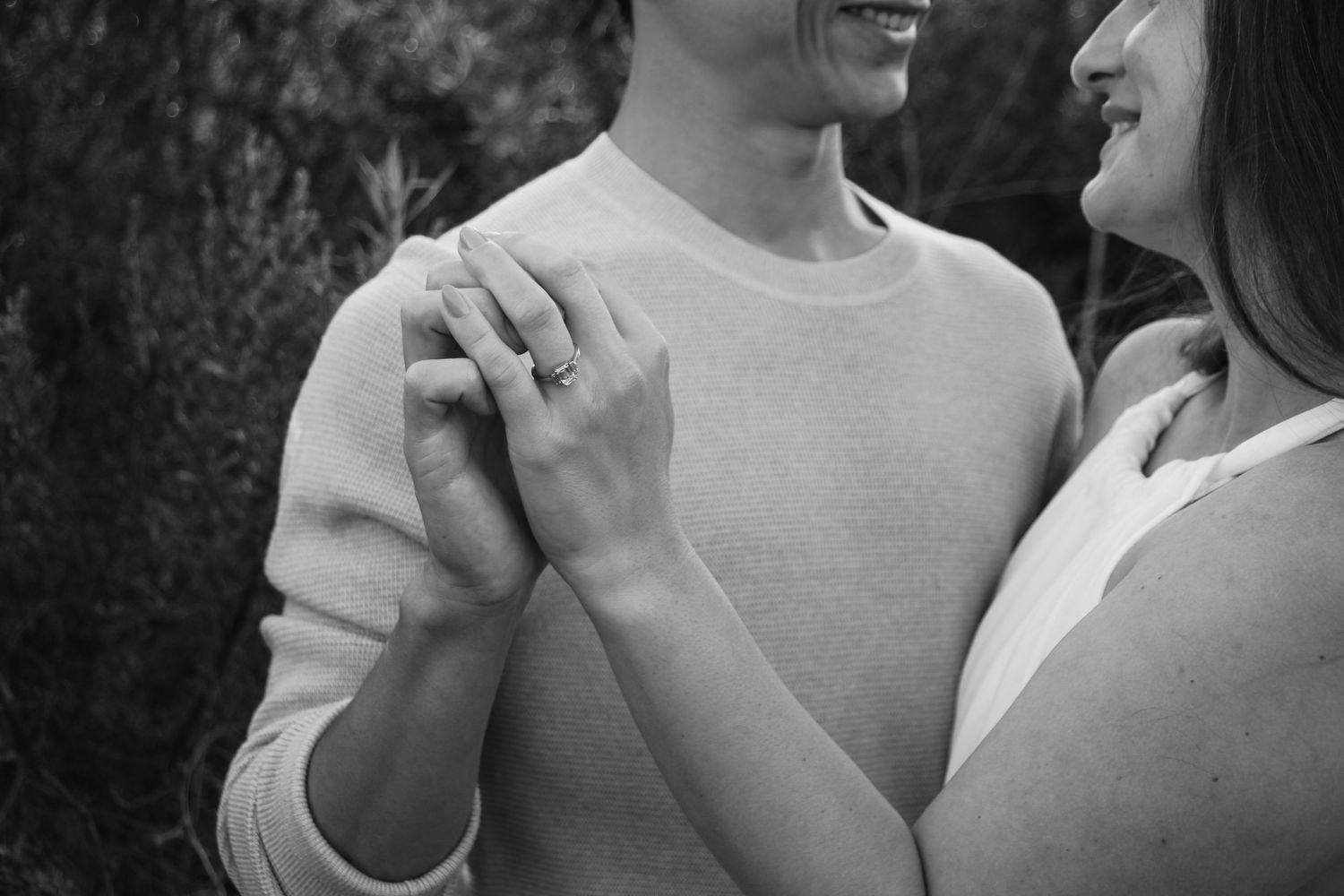 Close up black and white photo showing couple's hands and intimate embrace.