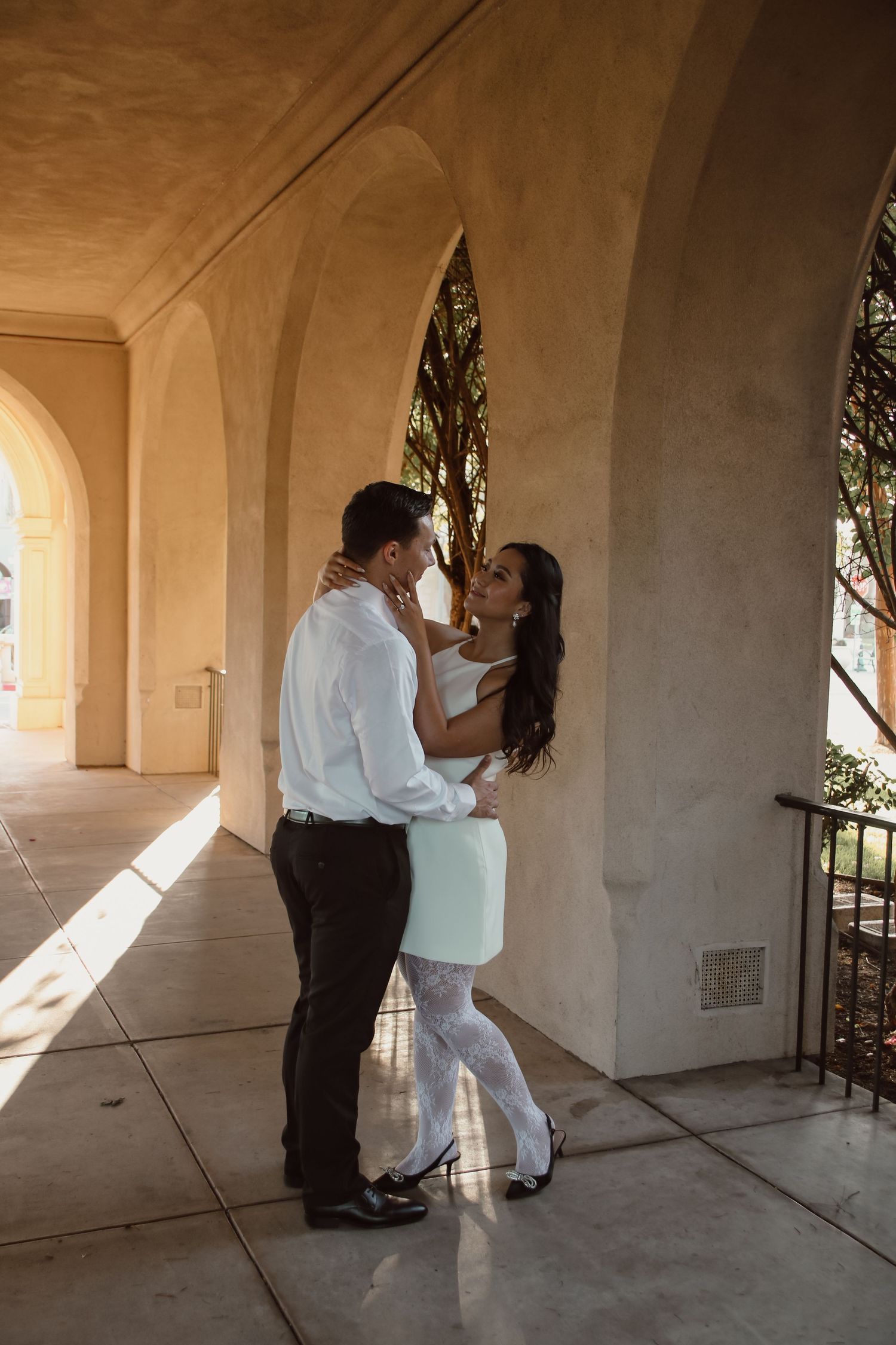 A couple embraces in a series of black and white photos under architectural arches.