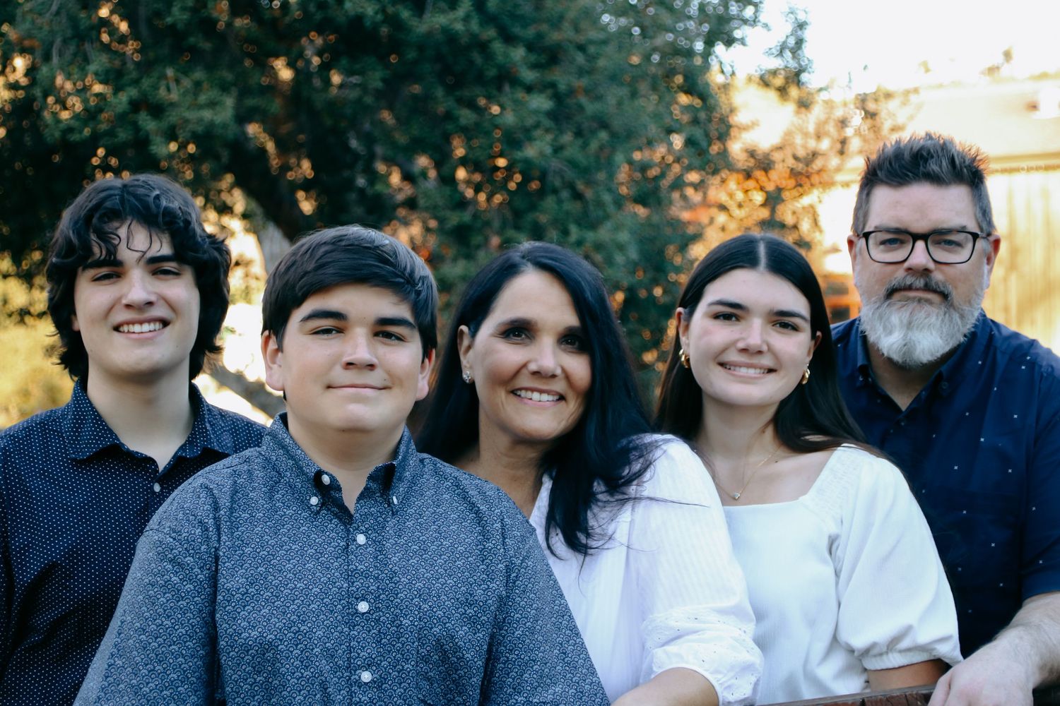 Relaxed outdoor group photo with warm evening light filtering through trees.