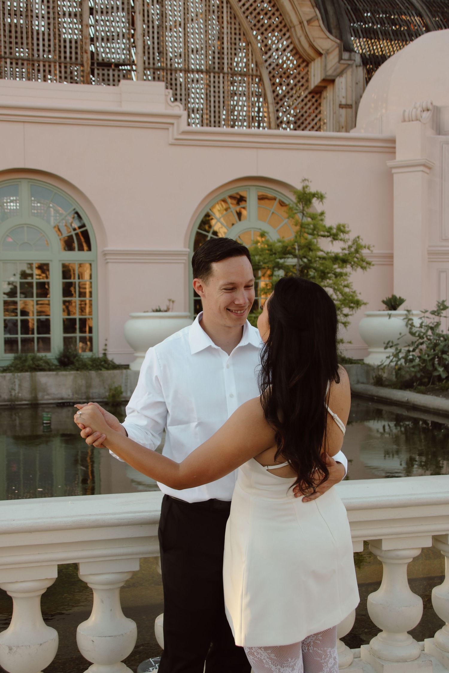 Dancing couple in coordinated outfits share a tender moment by an arched architectural feature.