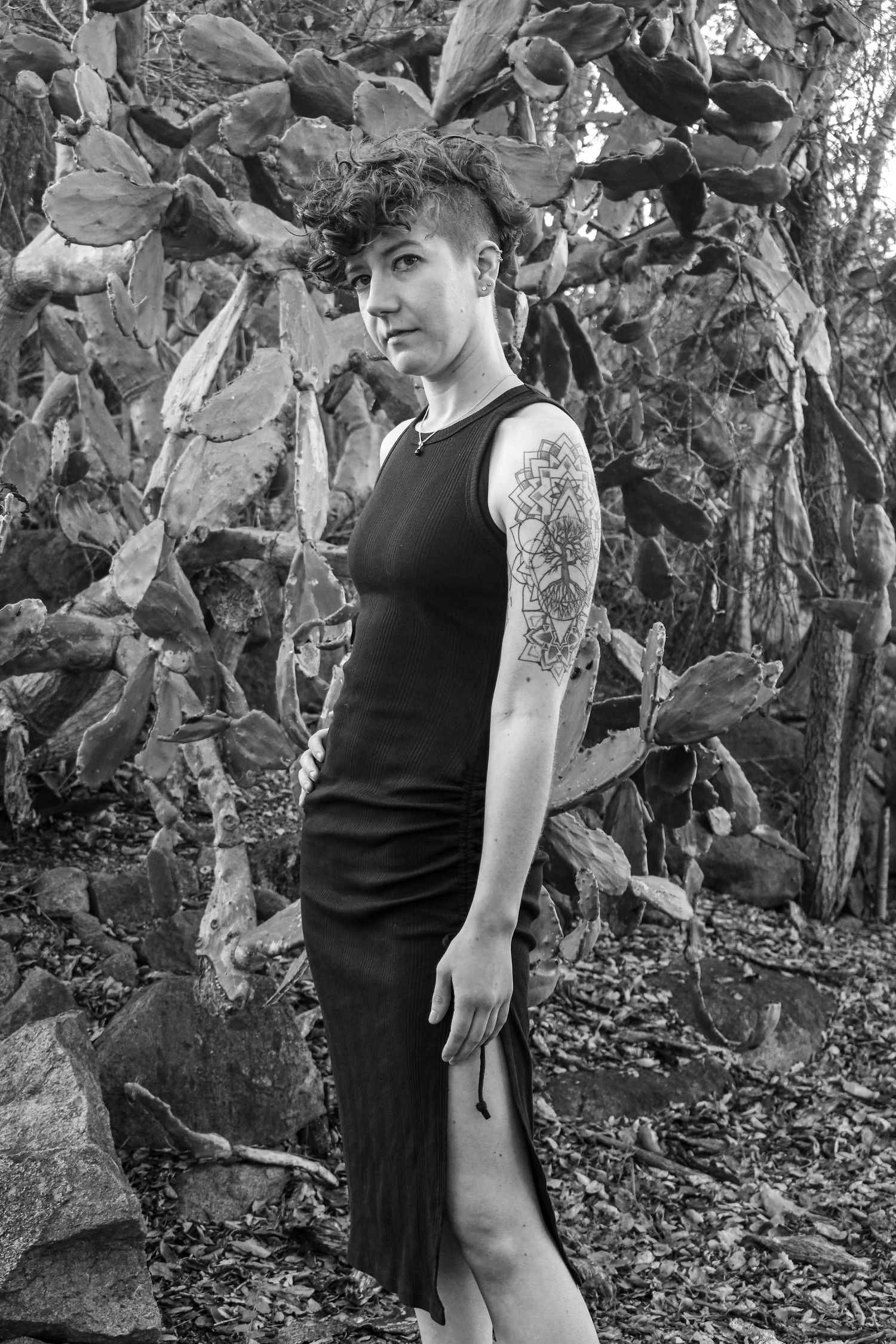 Black and white portrait against cactus backdrop showcasing elegant black dress.