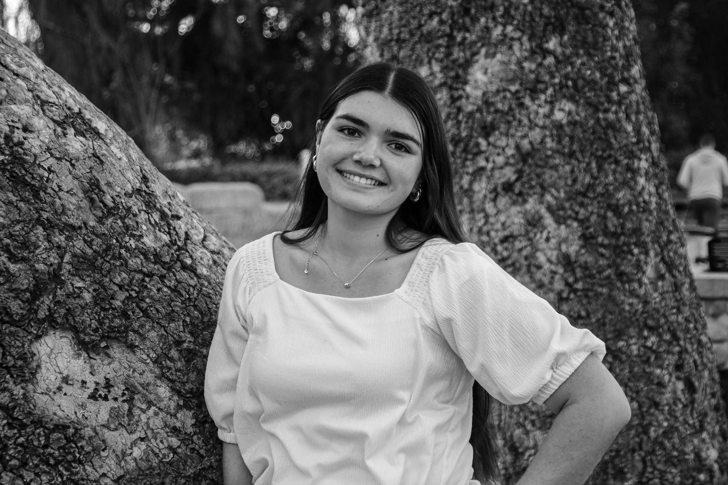Black and white portraits of people sitting near a large tree trunk.