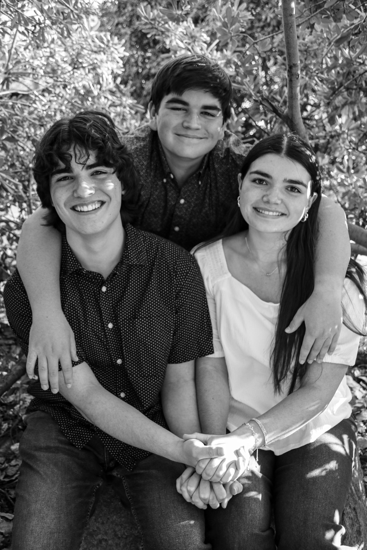 Black and white series of candid moments between three people sitting close together outdoors.
